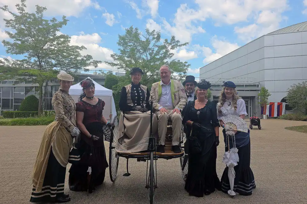 Event 111 Jahre Mercedes Bens Werk Sinderfingen Stephan Masur und historische Statisten Stephan Masur und Menschen in einerm ersten historischen Dreirad von Mercedes Benz