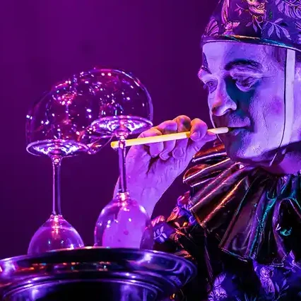 Ein Clown macht eine Riesenrad aus Seifenblasen auf zwei Gläsern