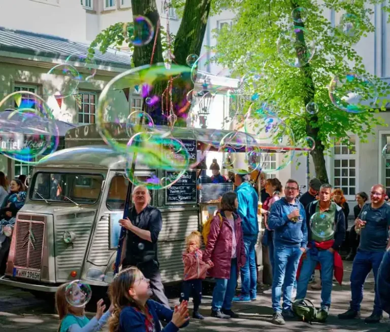 Stephan Masur Seifenblasen Walkact beim Hänneschen Theaterfest in Köln Ein Seifenblasenkünstler macht Seifenblasen umgeben von staunendem Publikum
