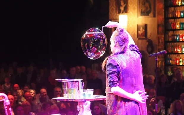 Seifenblasen Bühnenshow Ein Artiste mache ien große Seifenblase in einer Bühnenshow
