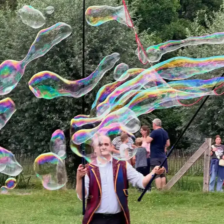 Ein Mann macht gorsse Seifenblasen in einem bunten Kostüm