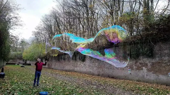 Riesenseifenblase 7m lang Stephan Masur Ein Junge erzeugt bunte Seifenblasen in einem herbstlichen Park.