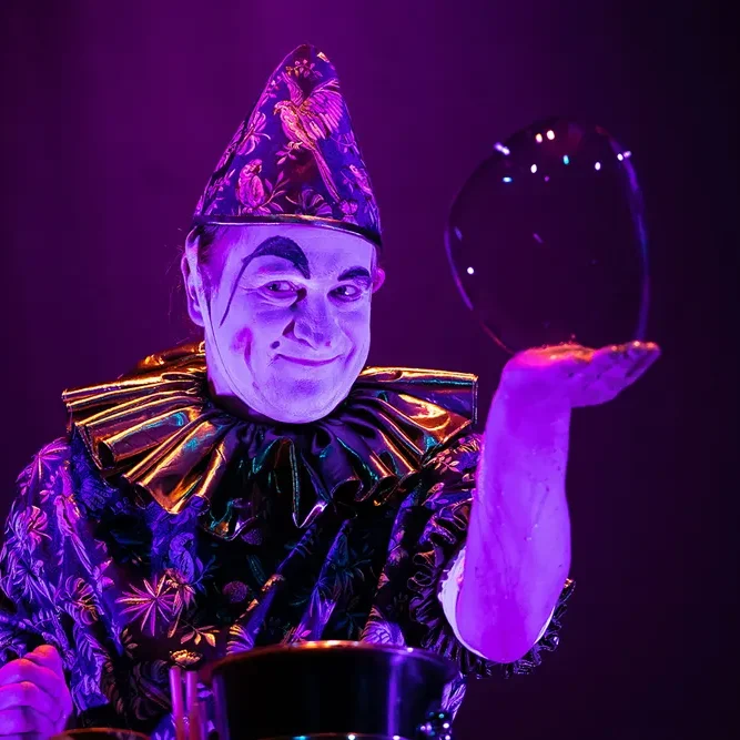 Seifenblasenshow für Karnevalssitzung: Kinder und Erwachsene erleben magische Seifenblasen live Ein Clown in glitzerndem Kostüm hält eine schimmernde Seifenblase in der Hand.