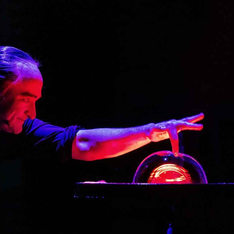 Mann berührt eine leuchtende Glaskugel mit rotem Licht.