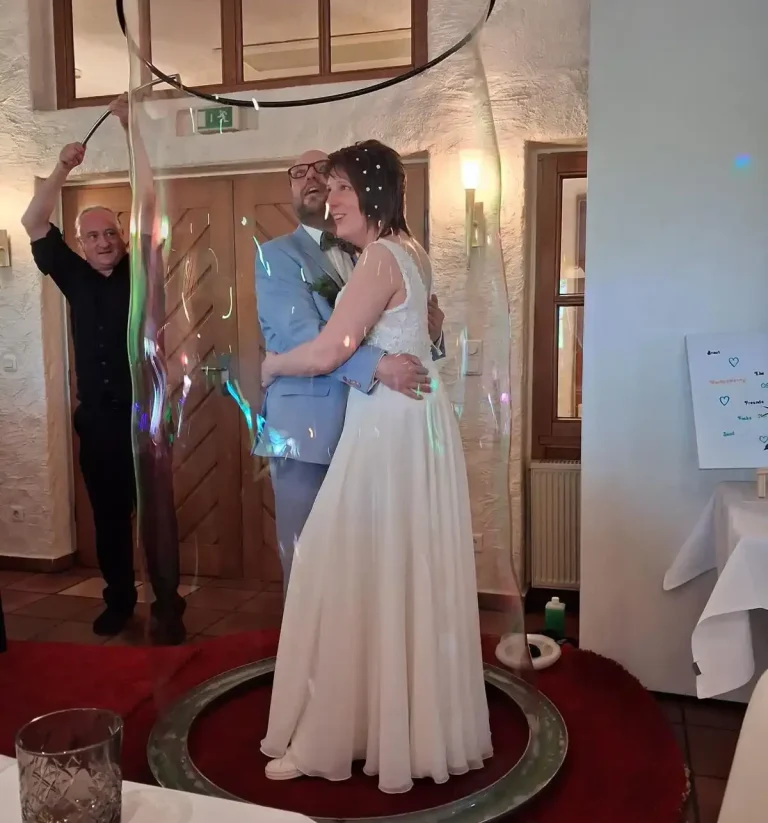 hochzeit seifenblasenshow mensch in blase Eine Frau steht in einem Hula-Hoop-Reifen, während ein Mann daneben posiert.