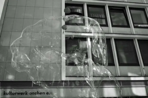 Riesenseifenblase Transparente Skulptur eines Kopfes vor einem modernen Gebäude.