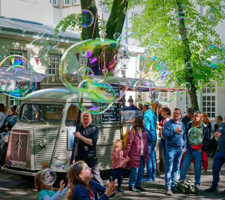 Hochzeit Seifenblasen walk act Eine Gruppe von Menschen steht um einen alten Truck, umgeben von großen Seifenblasen.
