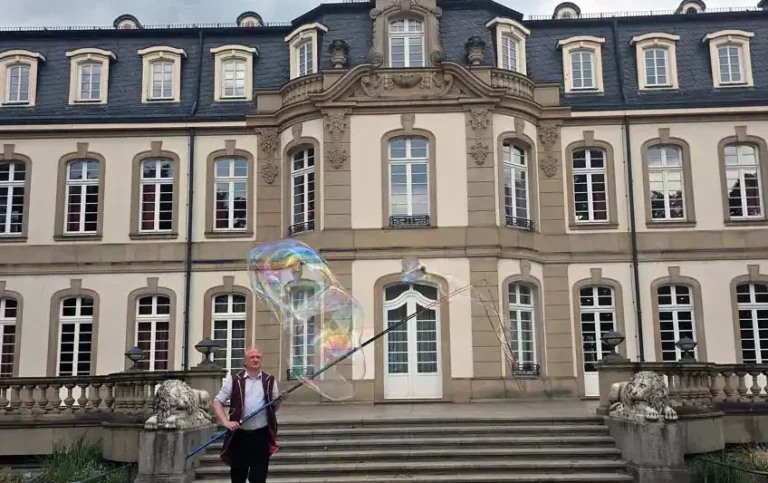 Seifenblasenkünstler mit Riesenseifenblasen Ein Clown macht Riesenseifenblasen vor einem Schloss