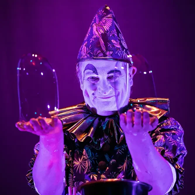 Der Clown-Charakter – Spielerisches Storytelling mit Seifenblasen Ein Clown mit glitzerndem Kostüm jongliert mit Seifenblasen auf der Bühne.