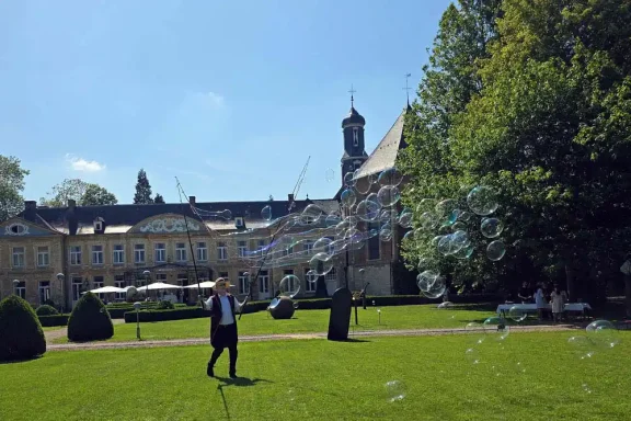 Seifenblasen Walkact St Gerlach Ein Mann steht auf einer Wiese vor einem historischen Gebäude mit Bubbles im Hintergrund.