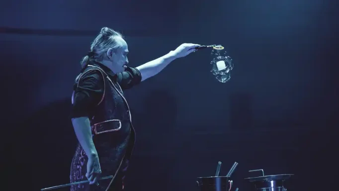 Viereckige Seifenblase in der Seifenblasenshow von Stephan Masur Ein Zauberkünstler präsentiert eine Illusion auf einer dunklen Bühne.