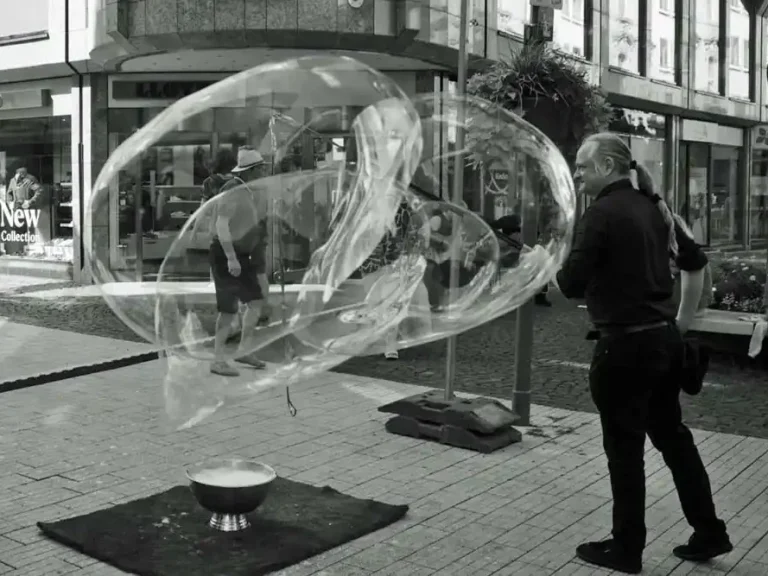 Ein Mann macht grosse Seifenblasen auf der Strasse