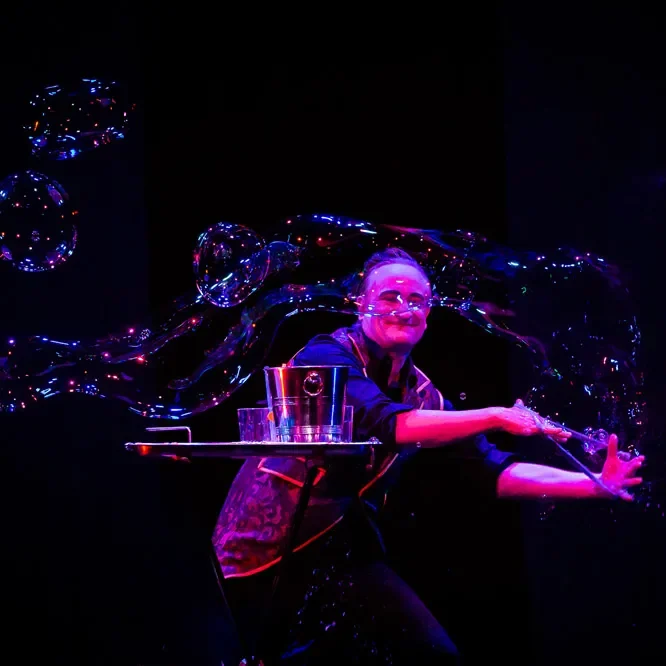 Stephan Masur Riesenseifenblasen im Varieté Ein Zauberer formt große Seifenblasen auf einer Bühne.